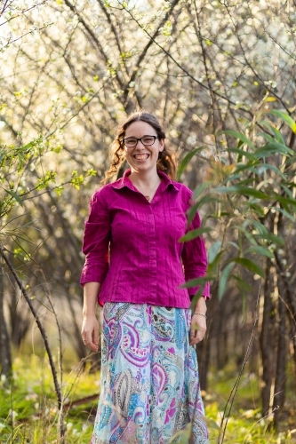 Portrait of a smiling young woman surrounded by white spring blossoms - Australian Stock Image