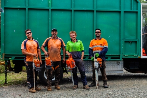 Portrait of a team of men who are tree felling lumberjacks with their chainsaws in front of truck - Australian Stock Image