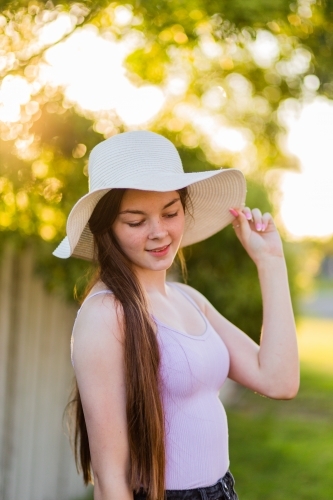 Portrait of a teenage girl in a straw sun hat - golden bokeh backlighting