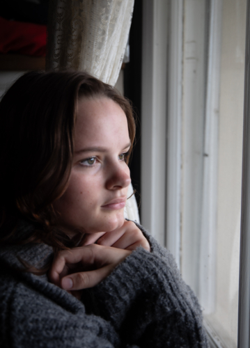 Portrait of a teenage girl looking out a window - Australian Stock Image