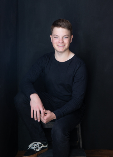 Portrait of a teenage male against black backdrop - Australian Stock Image
