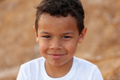 Portrait of a young aboriginal child against brown australian earth - Australian Stock Image