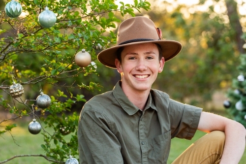 Portrait of a young Aussie teen sitting outside in summer at Christmastime - Australian Stock Image