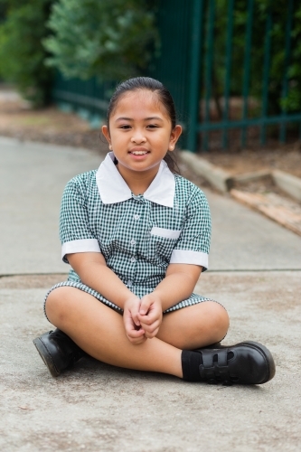 Portrait of a young Australian girl of Filipino ethnicity sitting outside school - Australian Stock Image
