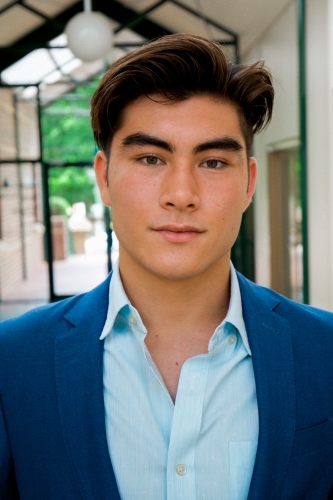 Portrait of a young male office worker standing near the exit of the building - Australian Stock Image