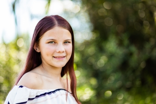 Portrait of a young pre-teen girl with copy space and natural green background