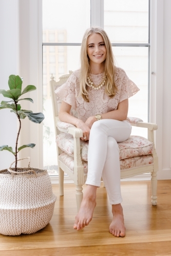 Portrait of a young professional woman sitting in a vintage chair - Australian Stock Image