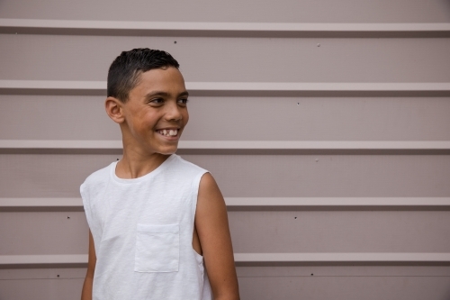 Portrait of a young, smiling first nations boy looking away - Australian Stock Image