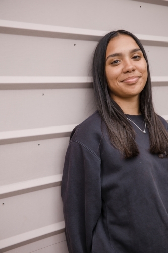 Portrait of a young, smiling,  first nations woman against wall outside - Australian Stock Image