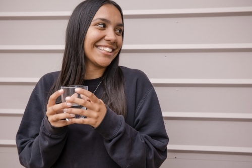 Portrait of a young, smiling, first nations woman holding  a glass of water - Australian Stock Image