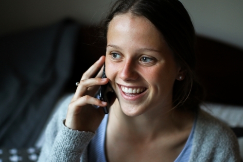 Portrait of a young teenage girl talking on her phone indoors - Australian Stock Image
