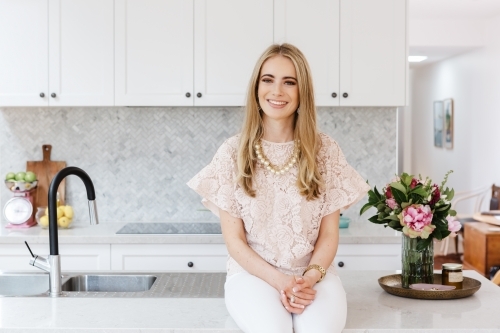 Portrait of an interior designer sitting on a kitchen bench - Australian Stock Image