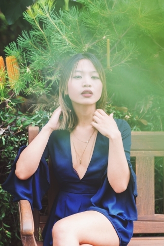 portrait of beautiful asian woman sitting on park bench - Australian Stock Image