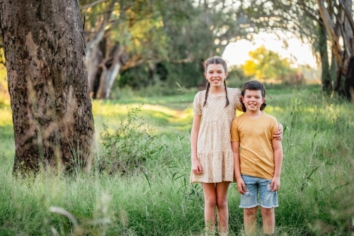 Portrait of bother and sister standing together in Australian country bush setting