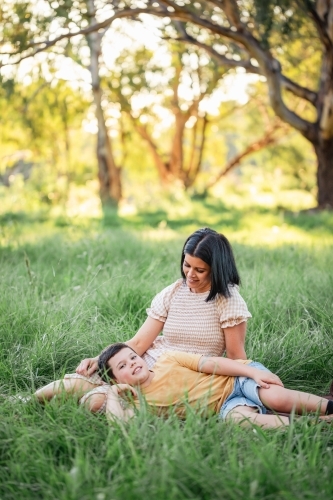 Portrait of boy lying on mothers lap in rural country bush setting - Australian Stock Image