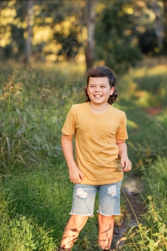 Portrait of happy boy wearing yellow shirt in Australian country bush setting - Australian Stock Image