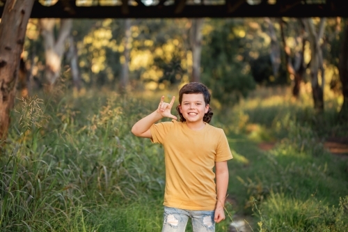 Portrait of happy boy wearing yellow shirt in Australian country bush setting - Australian Stock Image