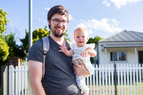 Portrait of happy father with daughter outside of house with picket fence going out together - Australian Stock Image