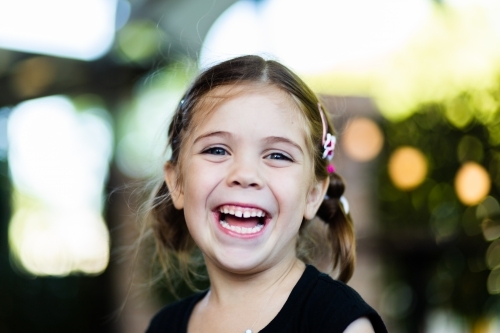Portrait of happy little six year old girl laughing with bokeh background - Australian Stock Image