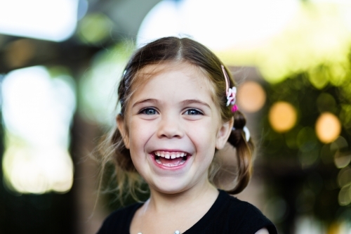 Portrait of happy little six year old girl laughing with bokeh background - Australian Stock Image