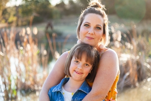 Portrait of happy mother in her thirties with daughter outside - Australian Stock Image