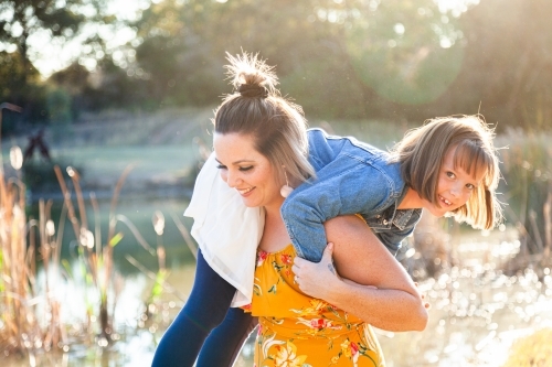 Portrait of happy mother in her thirties with daughter outside - Australian Stock Image