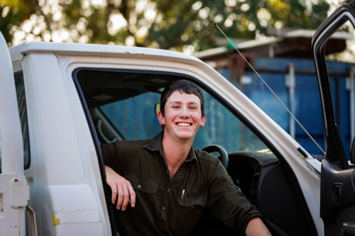 Portrait of happy smiling teenaged young man sitting in his first car a ute in country setting - Australian Stock Image