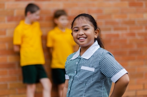 Portrait of happy young Aussie school girl of Filipino ethnicity smiling and wearing a dress - Australian Stock Image