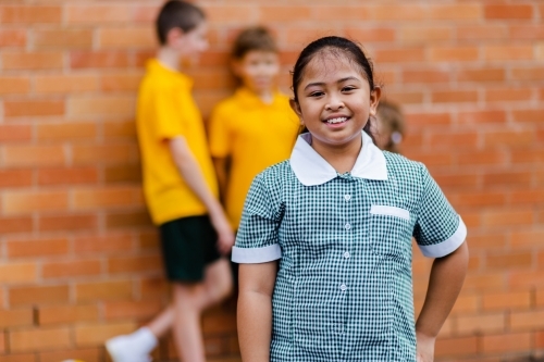 Portrait of happy young Aussie school girl of Filipino ethnicity smiling and wearing a dress - Australian Stock Image