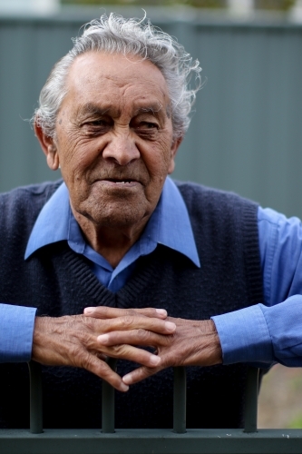 Portrait of male Aboriginal elder leaning on a fence - Australian Stock Image