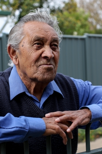 Portrait of male Aboriginal elder looking upwards while leaning on a fence - Australian Stock Image