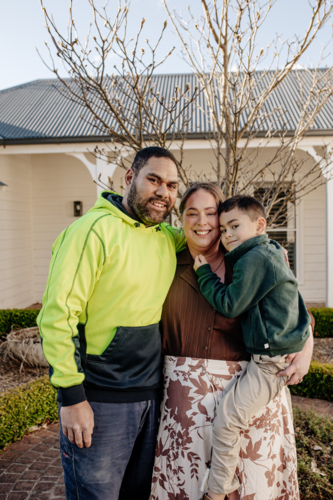 Portrait of mixed ethnicity couple with mum carrying son outdoors - Australian Stock Image
