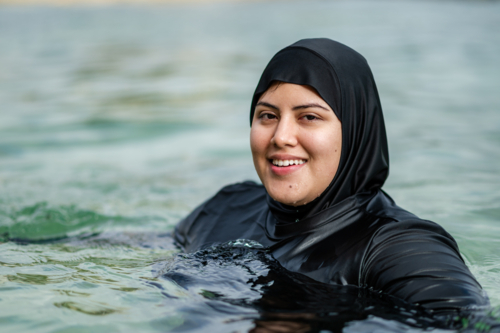 Portrait of mixed-race woman in burkini inside ocean pool on sunny day - Australian Stock Image