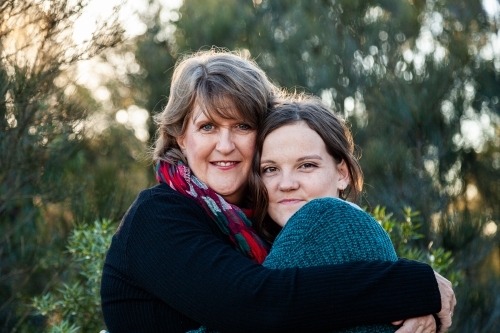 Portrait of mother and daughter embracing in hug - Australian Stock Image