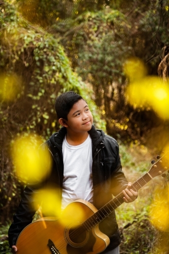 Portrait of musician through trees bokeh foreground - Australian Stock Image
