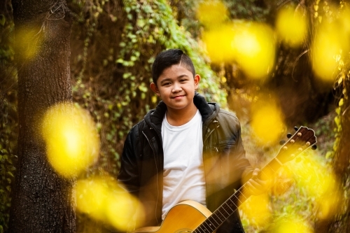 Portrait of musician through trees bokeh foreground - Australian Stock Image