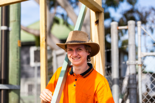portrait of smiling young bloke working on jobsite during hands on apprenticeship trade course - Australian Stock Image