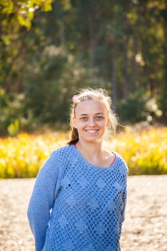 Portrait of smiling young woman in blue jumper - Australian Stock Image