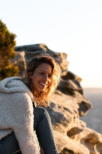 Portrait of smiling young woman on coastal clifftop at sunrise - Australian Stock Image