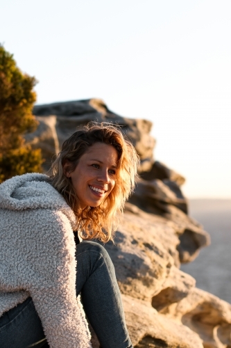 Portrait of smiling young woman on coastal clifftop at sunrise