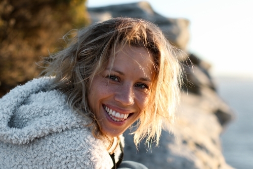 Portrait of smiling young woman on coastal clifftop at sunrise - Australian Stock Image