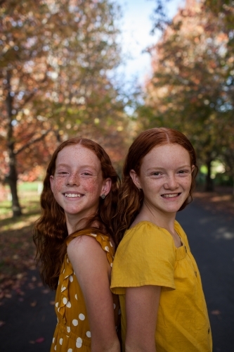 Portrait of two girls in a street lined with Autumn trees - Australian Stock Image