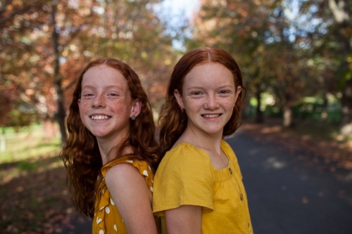 Portrait of two girls in a street lined with Autumn trees - Australian Stock Image
