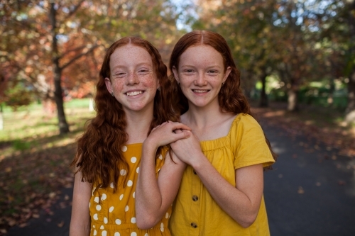 Portrait of two girls in a street lined with Autumn trees - Australian Stock Image
