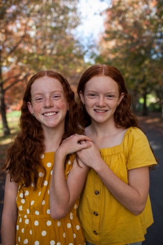 Portrait of two girls in a street lined with Autumn trees - Australian Stock Image