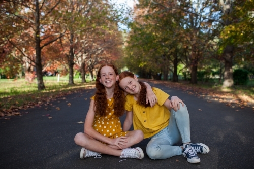 Portrait of two girls in a street lined with Autumn trees - Australian Stock Image