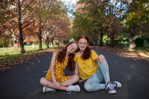 Portrait of two girls in a street lined with Autumn trees - Australian Stock Image