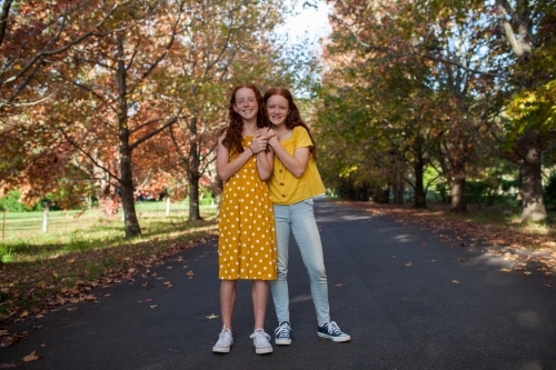 Portrait of two girls in a street lined with Autumn trees - Australian Stock Image