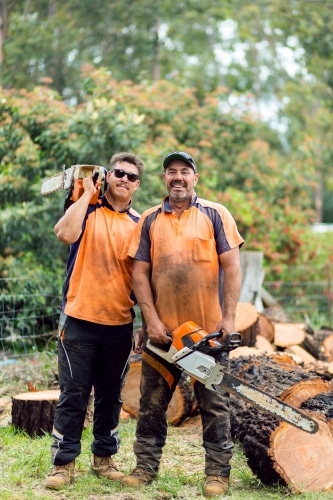Portrait of two happy aussie blokes with chainsaws - lumberjack tree felling services