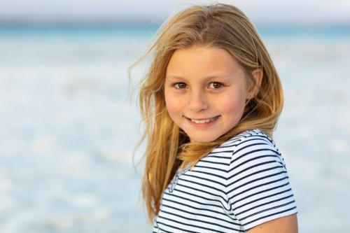 Portrait of vibrant young girl wearing striped shirt at the beach - Australian Stock Image